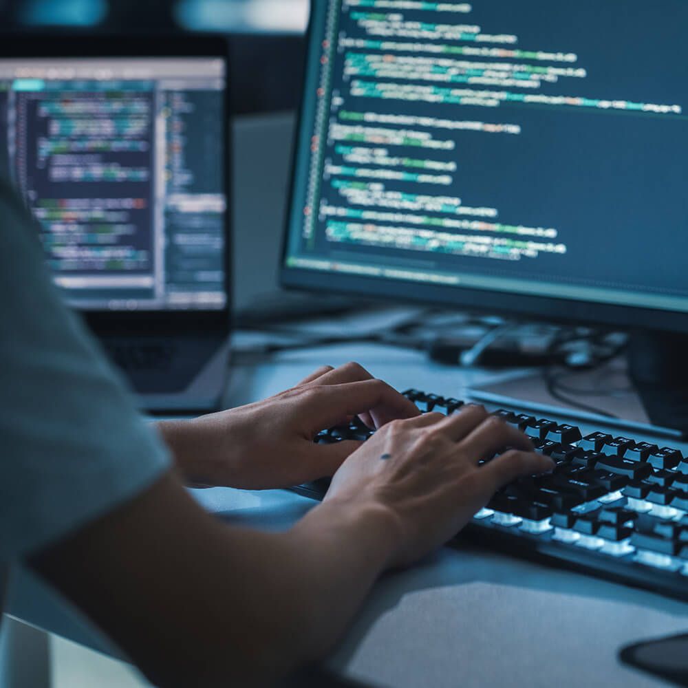 Mann bedient Computertastatur, Bildschirm zeigt Code