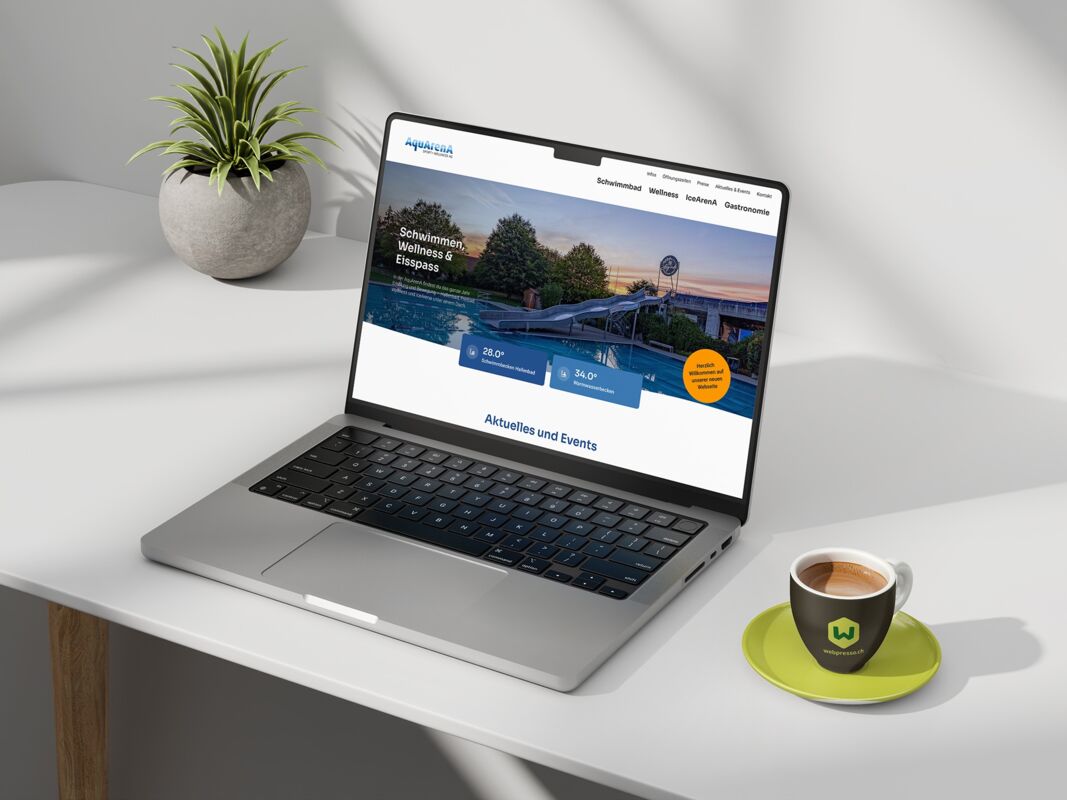 Laptop auf einem weissen Tisch mit einer Website auf dem Bildschirm und einer Tasse daneben