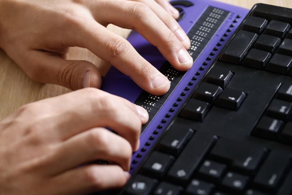 Hände bedienen eine Tastatur mit Braille-Zeile und zusätzlichen Bedienelementen