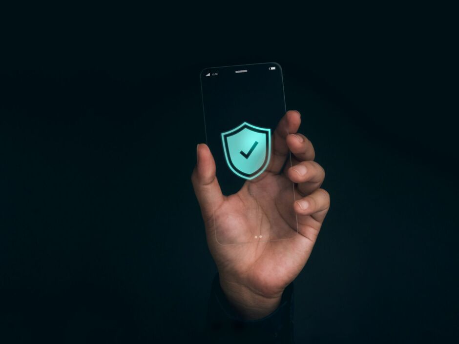 Hand hält ein Smartphone mit einem grünen Schild und einem weißen Haken darin